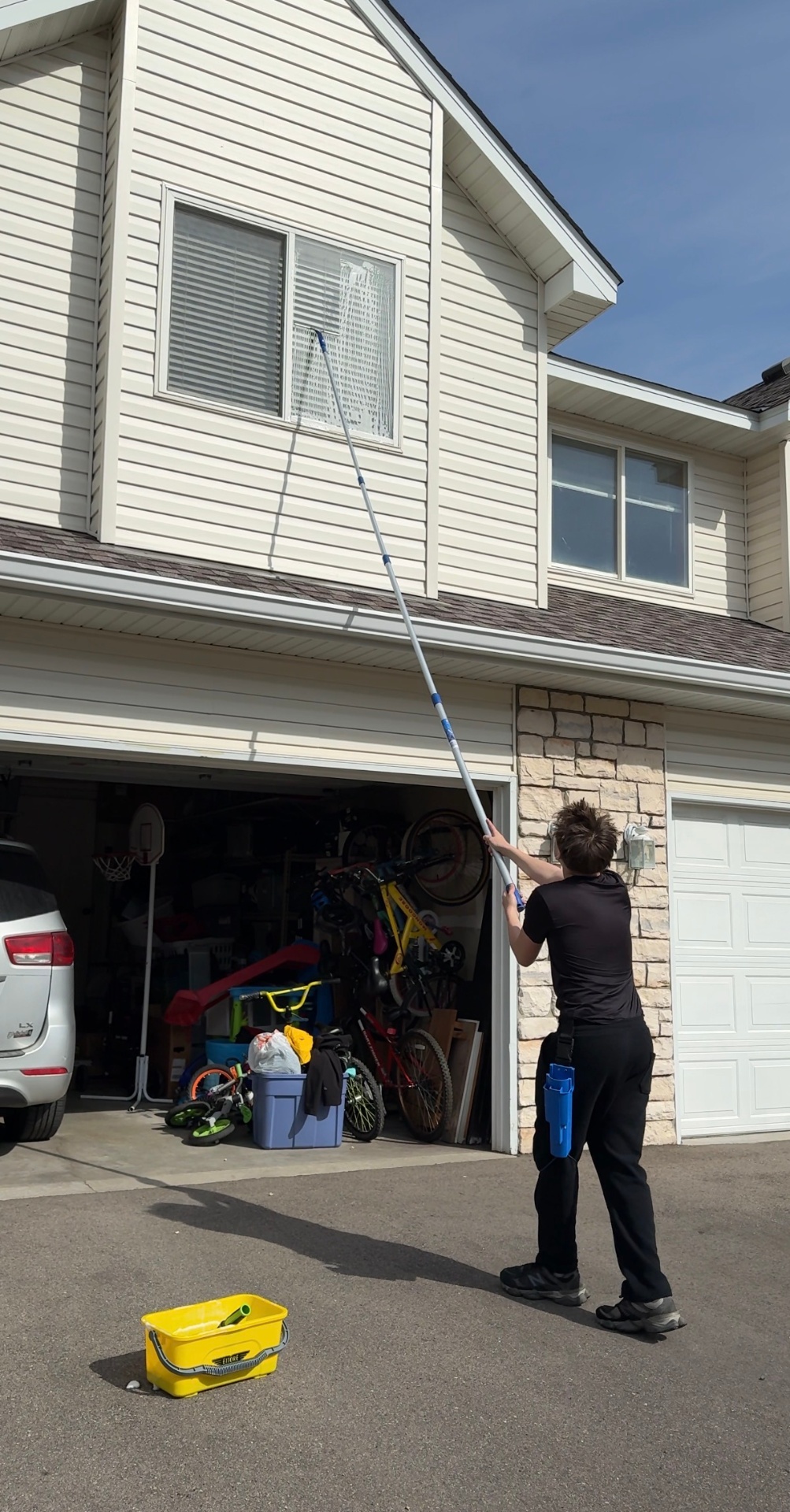 Brecken cleaning second-story windows with an extension pole